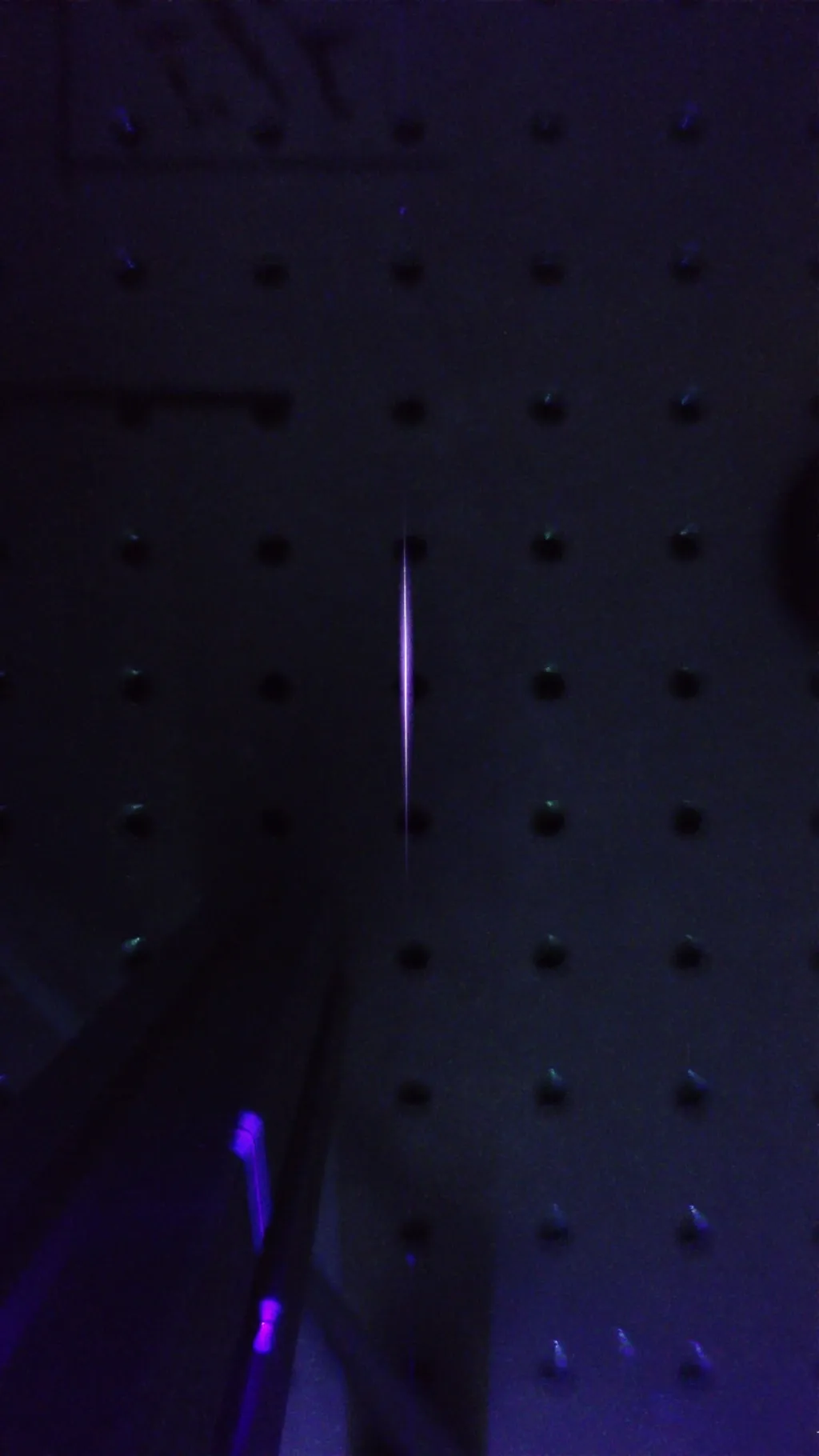 Fino filamento luminoso gerado por um laser em laboratório escuro