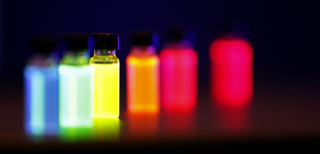Frascos com líquidos fluorescentes em várias cores sob luz ultravioleta